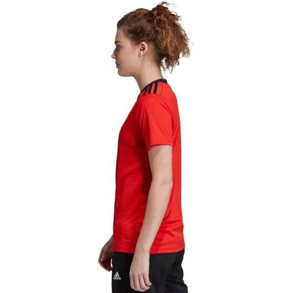 Woman wearing a red Adidas soccer jersey.