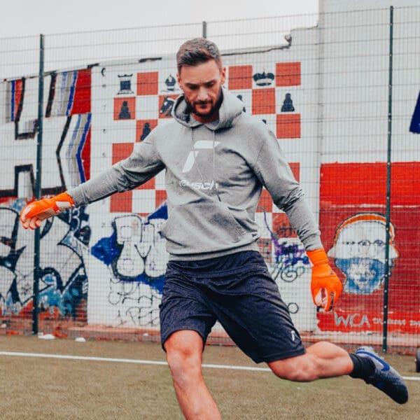 Man wearing a grey hoodie plays soccer.