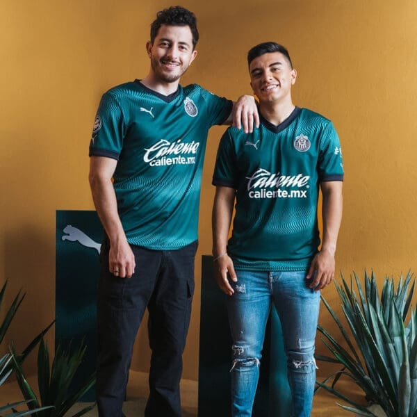 Two men wearing green soccer jerseys.