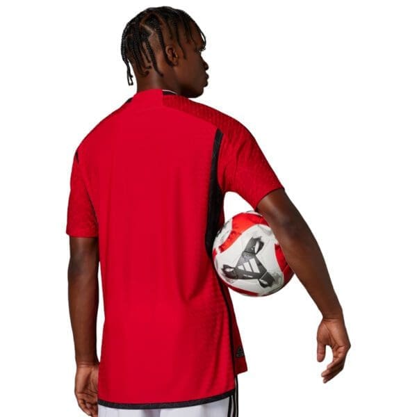 Man wearing a red soccer jersey with a ball.