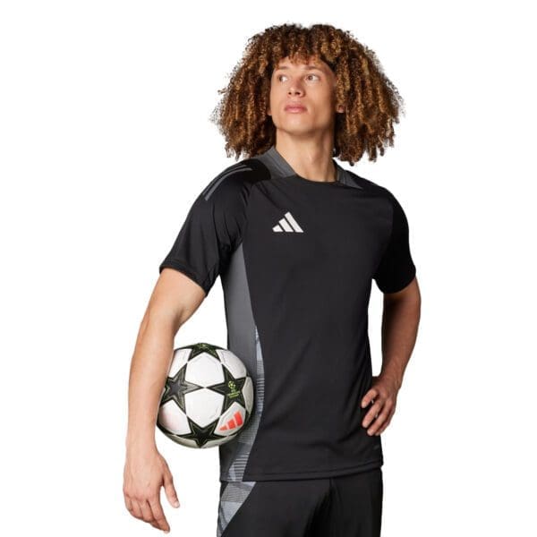 Man in black adidas soccer jersey holding ball.