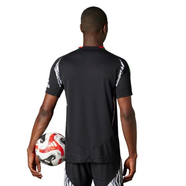 Man in black soccer jersey holding a ball.