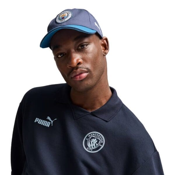 Man wearing Manchester City Puma hat and shirt.