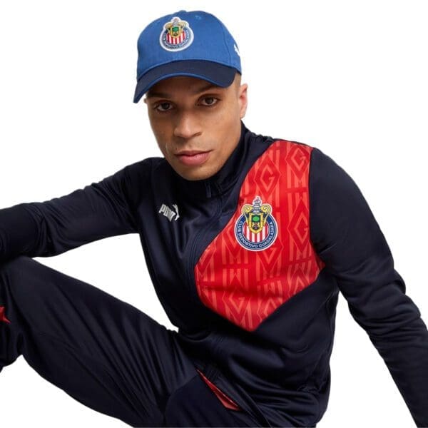 Man wearing blue and red tracksuit with a cap.