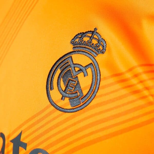 Real Madrid logo on orange jersey.