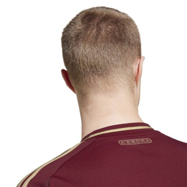 Man wearing burgundy and gold AS Roma jersey.