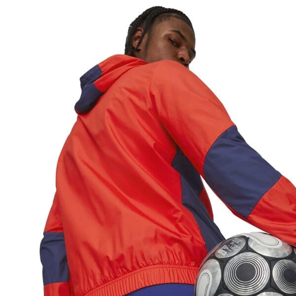 Man in red jacket holding a soccer ball.