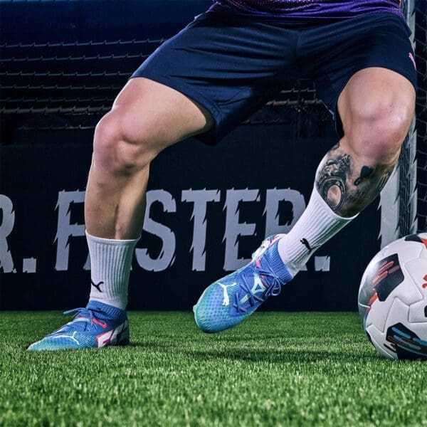 Soccer player wearing blue Puma cleats.