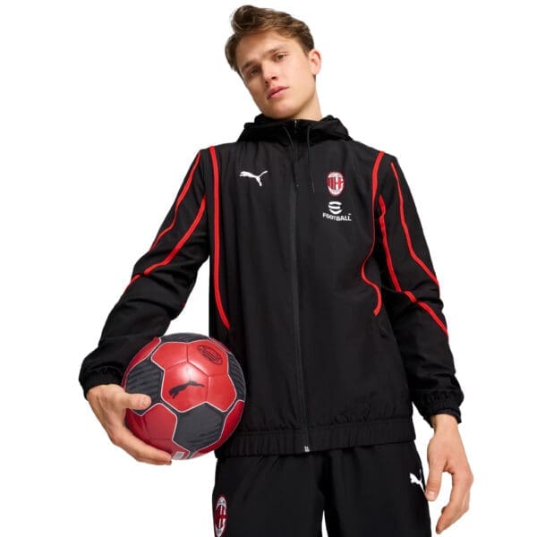 Man wearing AC Milan Puma jacket holding a soccer ball.