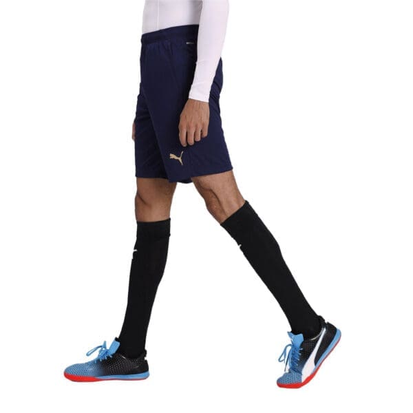 Man wearing blue Puma shorts and shoes.