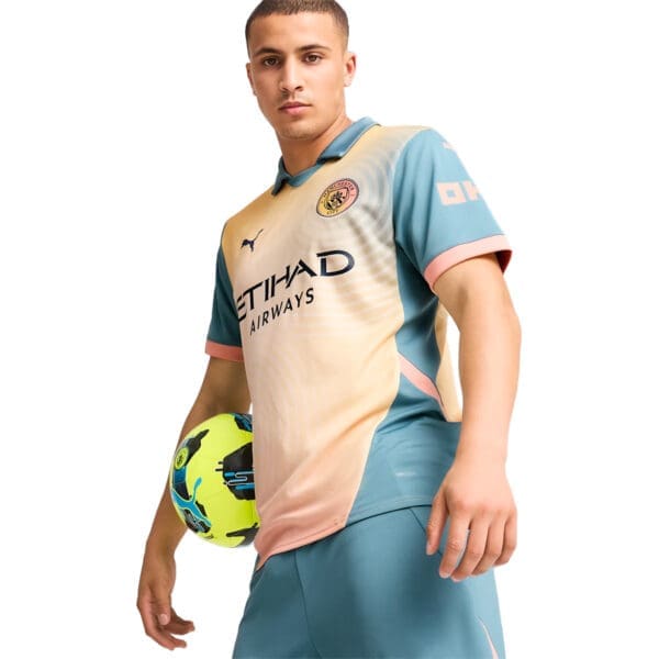 Man in Manchester City soccer uniform holding ball.