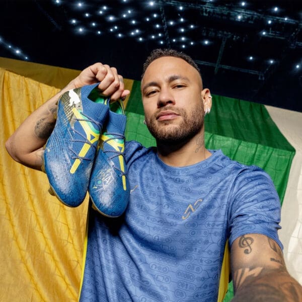 Neymar Jr. holding blue soccer cleats.