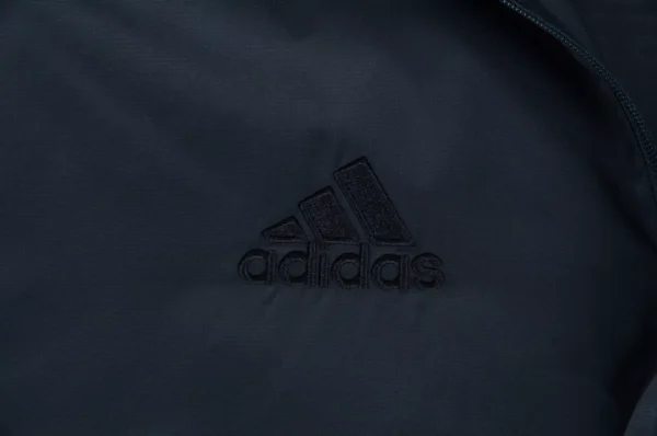 Black Adidas logo on dark fabric.