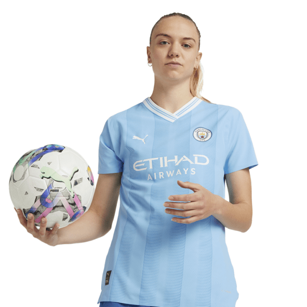 Woman in Manchester City jersey holding a soccer ball.