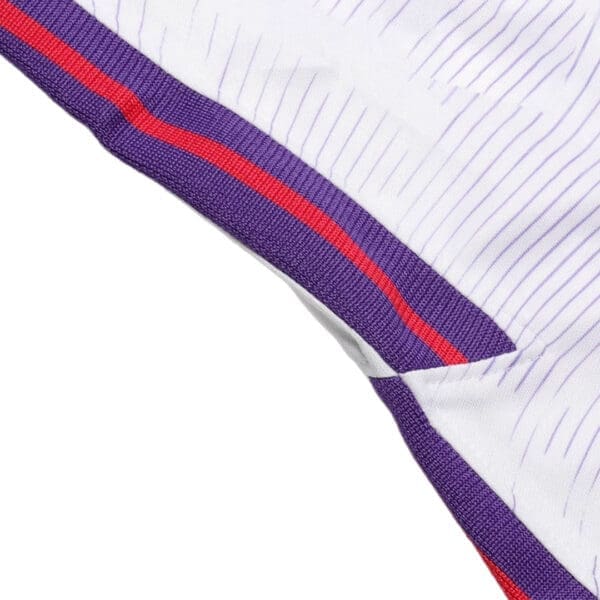 Close-up of a white jersey with purple and red trim.