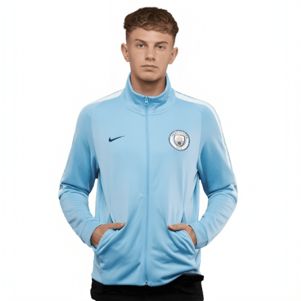 Man wearing light blue Manchester City jacket.