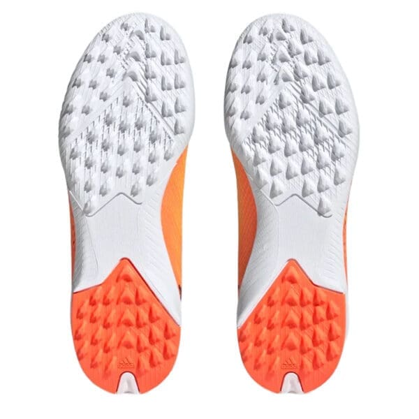 Orange and white Adidas soccer cleats, bottom view.